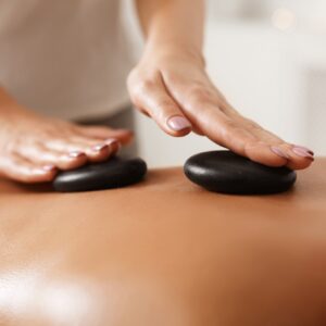 Masseur doing back hot stone massage, closeup